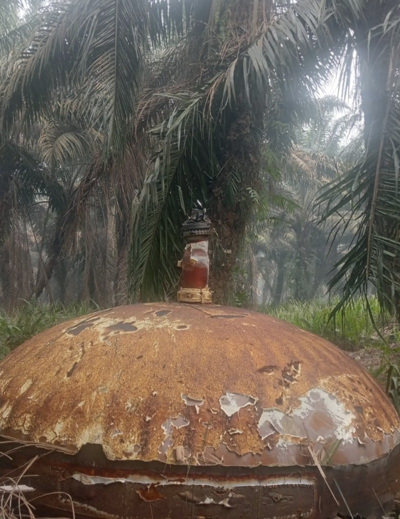 This picture taken on October 19, 2026 shows Indonesian police officers inspecting a large charred metallic fragment, suspected to be rocket debris, at an oil palm plantation in East Kotawaringin Regency, in Indonesia's Central Kalimantan province. Indonesian authorities were investigating October 20 after a piece of rocket the size of a car crashed into an oil palm plantation on Indonesian Borneo. (Photo by AHMAD SYIHAB / AFP)