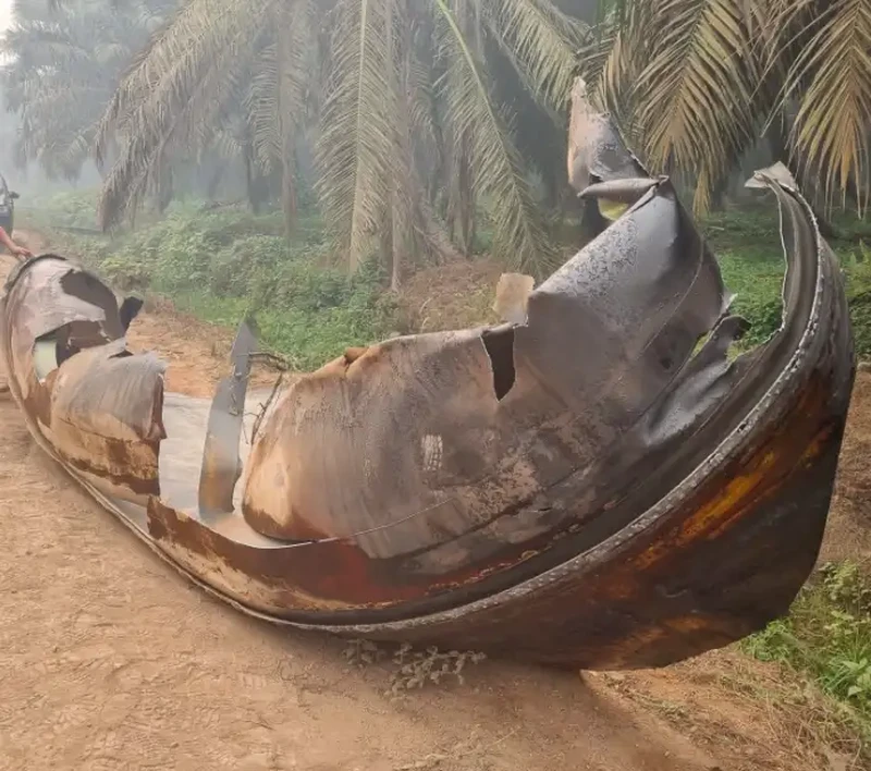 This picture taken on October 19, 2026 shows Indonesian police officers inspecting a large charred metallic fragment, suspected to be rocket debris, at an oil palm plantation in East Kotawaringin Regency, in Indonesia's Central Kalimantan province. Indonesian authorities were investigating October 20 after a piece of rocket the size of a car crashed into an oil palm plantation on Indonesian Borneo. (Photo by AHMAD SYIHAB / AFP)