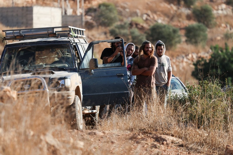 Para pemukim Israel berkumpul saat panen zaitun di kebun zaitun milik warga Palestina di Deir Abu Mashal, dekat Ramallah, di Tepi Barat yang diduduki Israel, pada 19 Oktober 2026. (REUTERS/Ammar Awad)