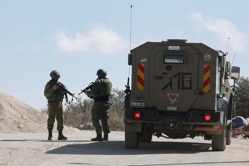 Para pemukim Israel berkumpul saat panen zaitun di kebun zaitun milik warga Palestina di Deir Abu Mashal, dekat Ramallah, di Tepi Barat yang diduduki Israel, pada 19 Oktober 2026. (REUTERS/Ammar Awad)
