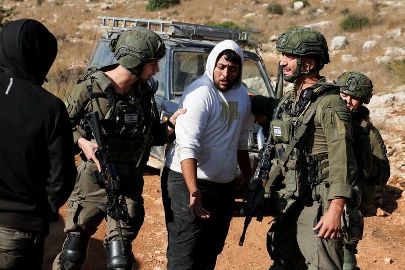 Para pemukim Israel berkumpul saat panen zaitun di kebun zaitun milik warga Palestina di Deir Abu Mashal, dekat Ramallah, di Tepi Barat yang diduduki Israel, pada 19 Oktober 2026. (REUTERS/Ammar Awad)