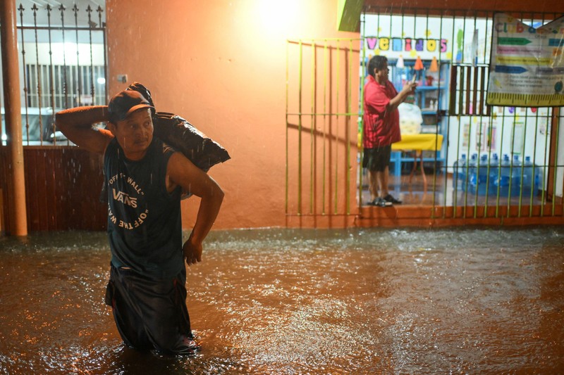 Warga mengarungi genangan banjir di sebuah jalan setelah hujan deras yang dipicu oleh Front Dingin Nomor 2 di Coatzacoalcos, negara bagian Veracruz, Meksiko, pada 19 Oktober 2026. (REUTERS/Angel Hernandez)