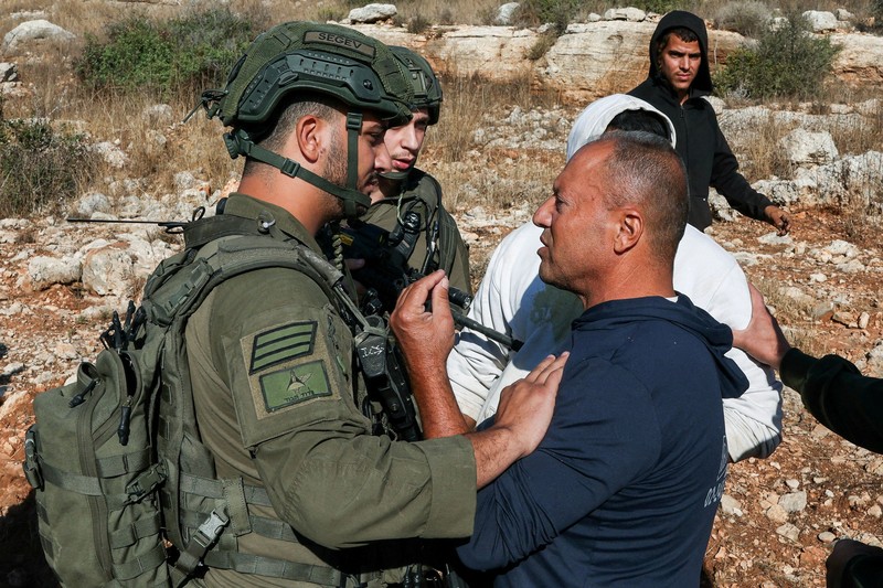 Para pemukim Israel berkumpul saat panen zaitun di kebun zaitun milik warga Palestina di Deir Abu Mashal, dekat Ramallah, di Tepi Barat yang diduduki Israel, pada 19 Oktober 2026. (REUTERS/Ammar Awad)