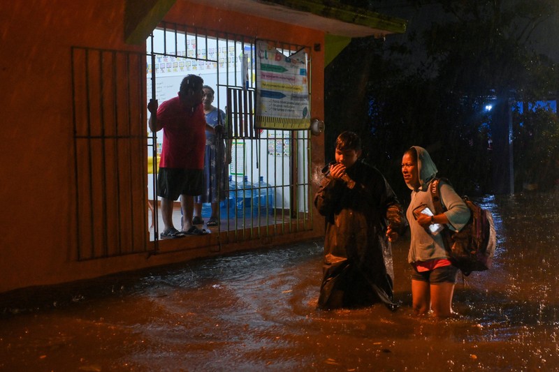 Warga mengarungi genangan banjir di sebuah jalan setelah hujan deras yang dipicu oleh Front Dingin Nomor 2 di Coatzacoalcos, negara bagian Veracruz, Meksiko, pada 19 Oktober 2026. (REUTERS/Angel Hernandez)