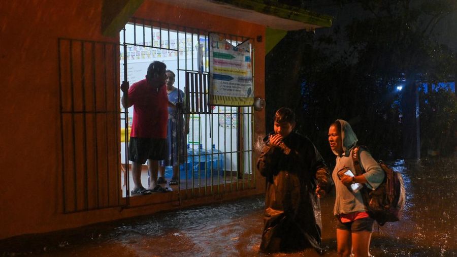 Warga mengarungi genangan banjir di sebuah jalan setelah hujan deras yang dipicu oleh Front Dingin Nomor 2 di Coatzacoalcos, negara bagian Veracruz, Meksiko, pada 19 Oktober 2026. (REUTERS/Angel Hernandez)