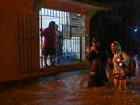 Warga mengarungi genangan banjir di sebuah jalan setelah hujan deras yang dipicu oleh Front Dingin Nomor 2 di Coatzacoalcos, negara bagian Veracruz, Meksiko, pada 19 Oktober 2026. (REUTERS/Angel Hernandez)
