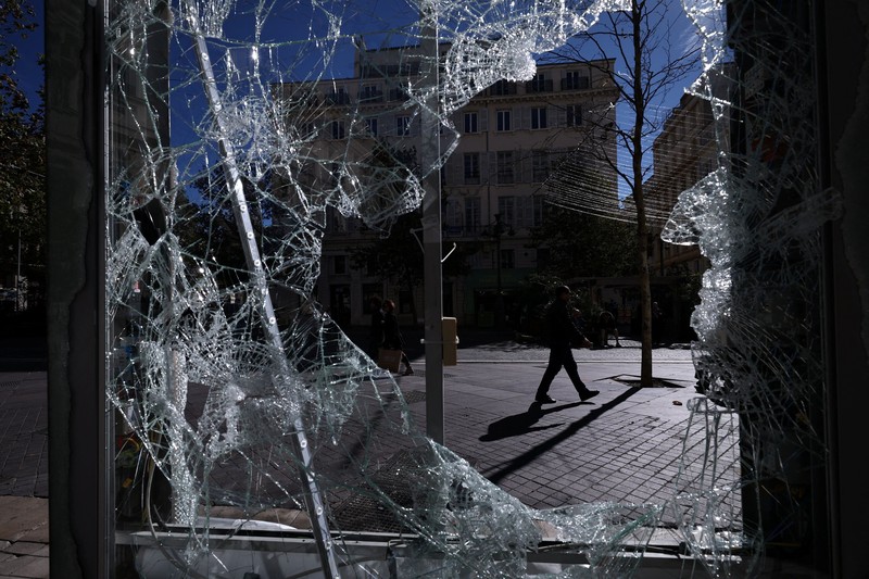 A man walks past stores with display windows protected by wooden panels days after nationwide protests against the cost of living and rising fuel prices called by the