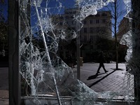 A person walking along a street is seen through a broken billboard days after nationwide protests against the cost of living and rising fuel prices called by the "Yellow Vests" movement and ahead of a second round of demonstrations, in Marseille, Fra