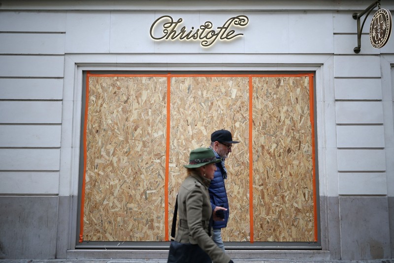 A man walks past stores with display windows protected by wooden panels days after nationwide protests against the cost of living and rising fuel prices called by the