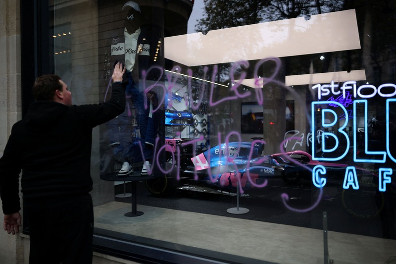A man walks past stores with display windows protected by wooden panels days after nationwide protests against the cost of living and rising fuel prices called by the