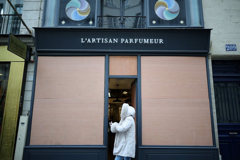 A man walks past stores with display windows protected by wooden panels days after nationwide protests against the cost of living and rising fuel prices called by the
