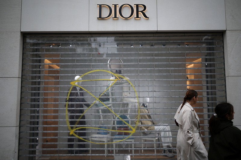 A man walks past stores with display windows protected by wooden panels days after nationwide protests against the cost of living and rising fuel prices called by the