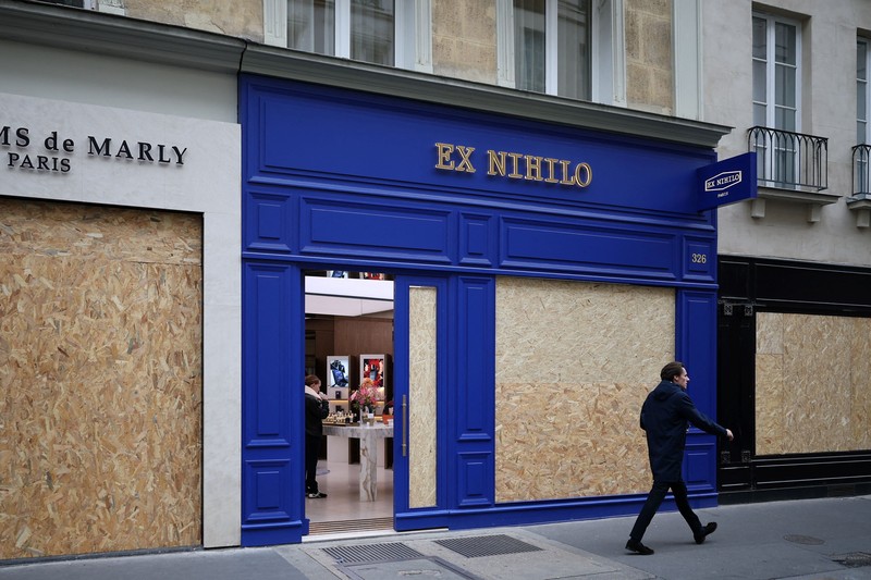 A man walks past stores with display windows protected by wooden panels days after nationwide protests against the cost of living and rising fuel prices called by the