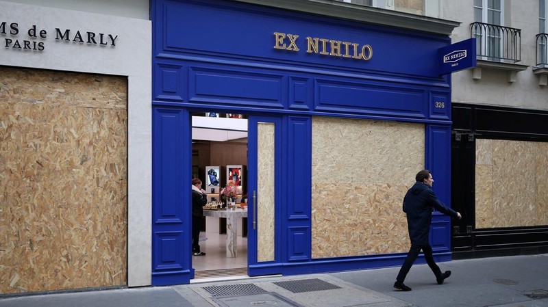 A man walks past stores with display windows protected by wooden panels days after nationwide protests against the cost of living and rising fuel prices called by the