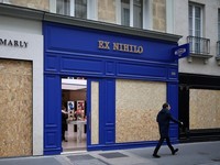 A man walks past stores with display windows protected by wooden panels days after nationwide protests against the cost of living and rising fuel prices called by the "Yellow Vests" movement and ahead of a second round of demonstrations in Paris, Fra