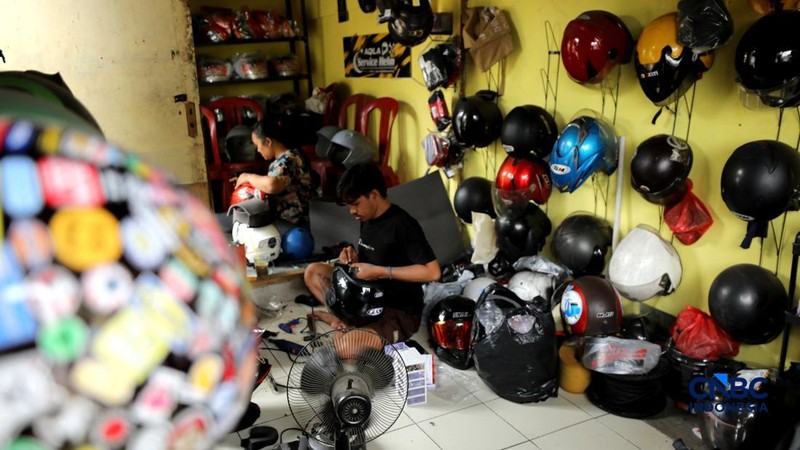 Pekerja melakukan perbaikan helm milik konsumen di salah satu gerai di kawasan Jakarta, Rabu (21/10/2026). (CNBC Indonesia/Tri Susilo)