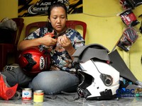 Pekerja melakukan perbaikan helm milik konsumen di salah satu gerai di kawasan Jakarta, Rabu (21/10/2026). (CNBC Indonesia/Tri Susilo)