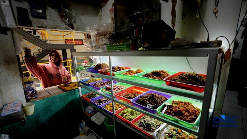 Pekerja membeli makanan dan minuman melalui lubang kecil di tembok pembatas kawasan permukiman dan pusat perbelanjaan di kawasan Kemang, Jakarta, Rabu (21/10/2026).