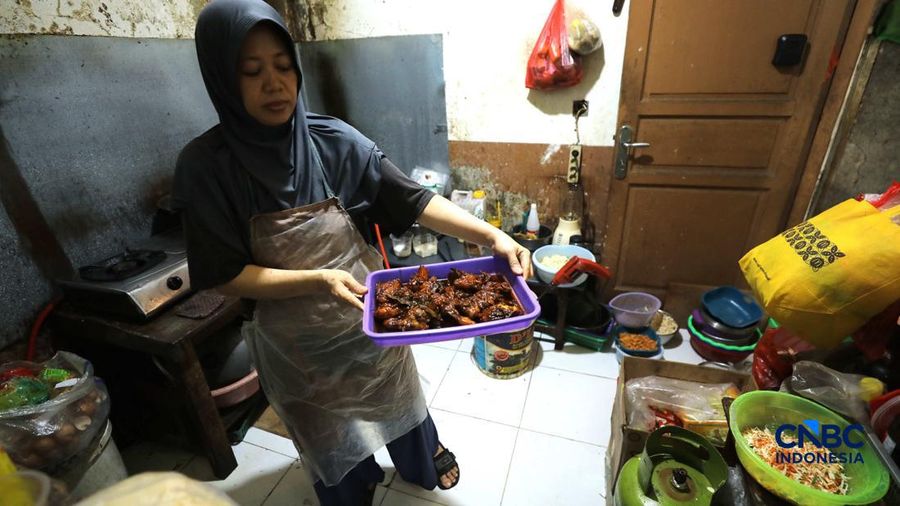Pekerja membeli makanan dan minuman melalui lubang kecil di tembok pembatas kawasan permukiman dan pusat perbelanjaan di kawasan Kemang, Jakarta, Rabu (21/10/2026).