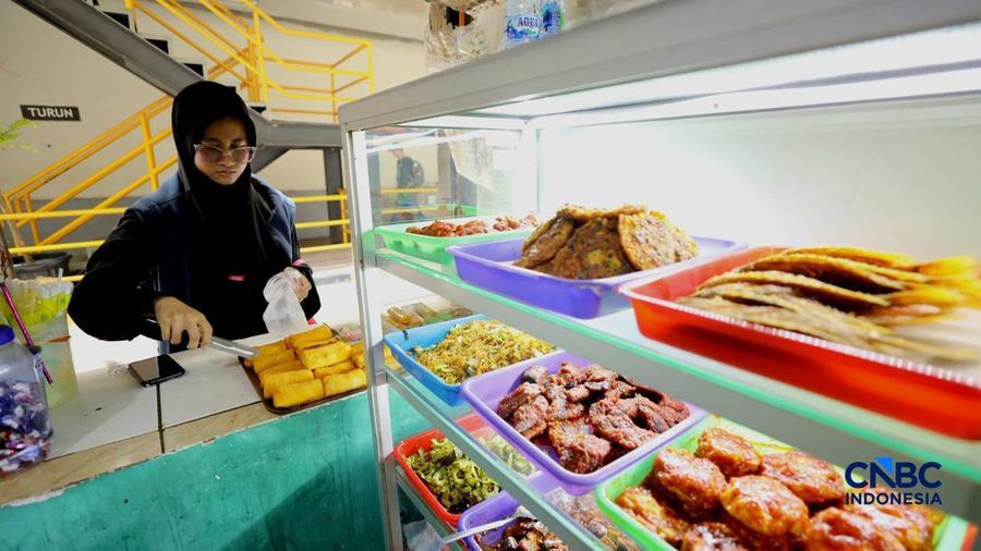 Pekerja membeli makanan dan minuman melalui lubang kecil di tembok pembatas kawasan permukiman dan pusat perbelanjaan di kawasan Kemang, Jakarta, Rabu (21/10/2026).