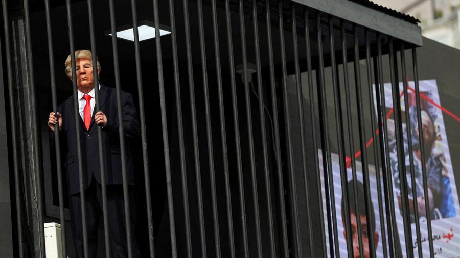 Iran membuat sindiran atau olok-olok terbaru terhadap Presiden Amerika Serikat (AS) Donald Trump, Rabu (21/10/2026). Iran membuat sosok tiruan Trump berada di balik jeruji besi yang dibuat di atas papan reklame. (via REUTERS/Majid Asgaripour)