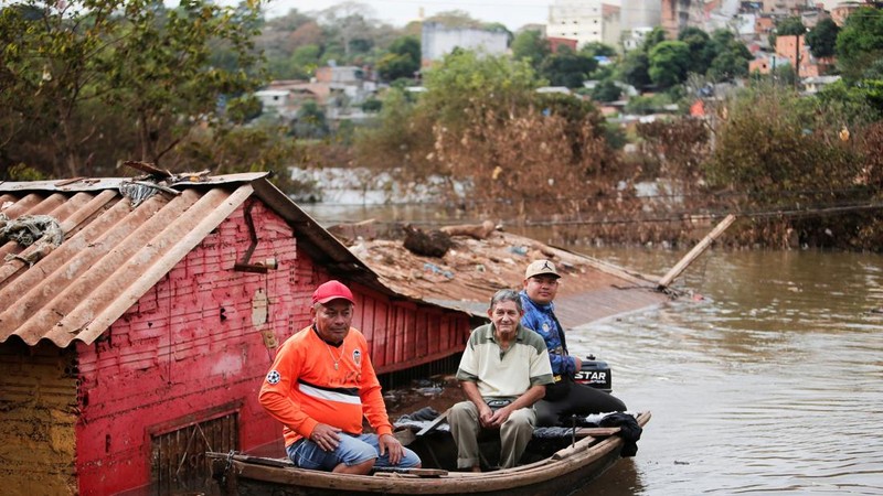 Warga bepergian menggunakan perahu melewati lingkungan yang terendam air setelah hujan deras menyebabkan banjir, di Ciudad del Este, Paraguay, 21 Oktober 2026.