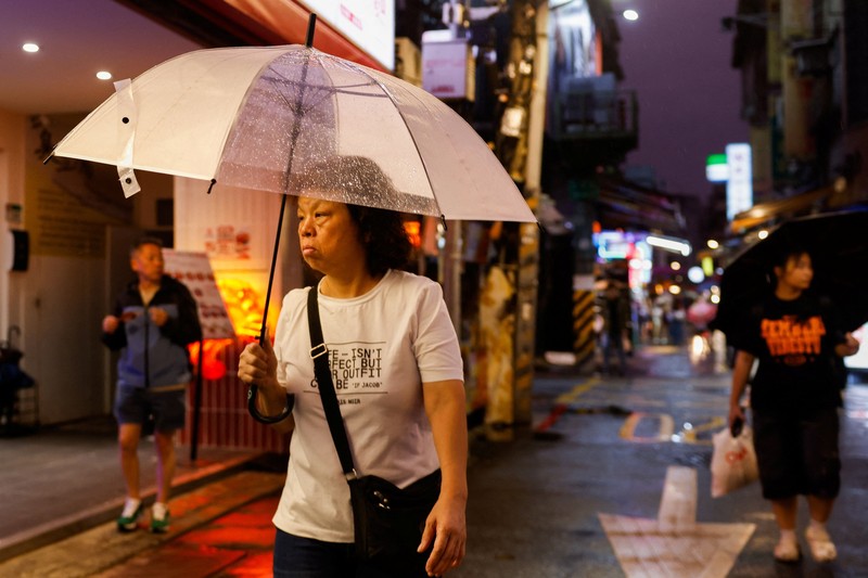Orang-orang membawa payung di tengah hujan saat Topan Champi mendekat, di Taipei, Taiwan, 22 Oktober 2026. (REUTERS/Ann Wang)