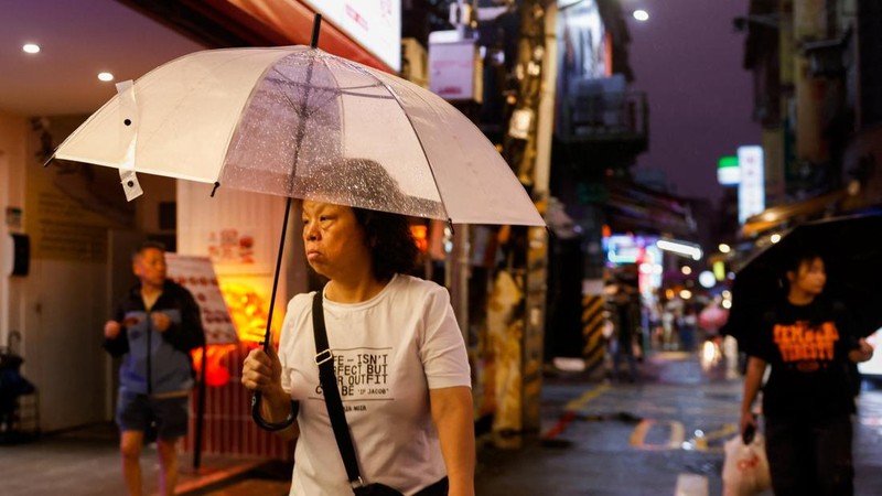 Orang-orang berjalan melewati pasar di tengah hujan saat Topan Champi mendekat, di Taipei, Taiwan, 22 Oktober 2026.