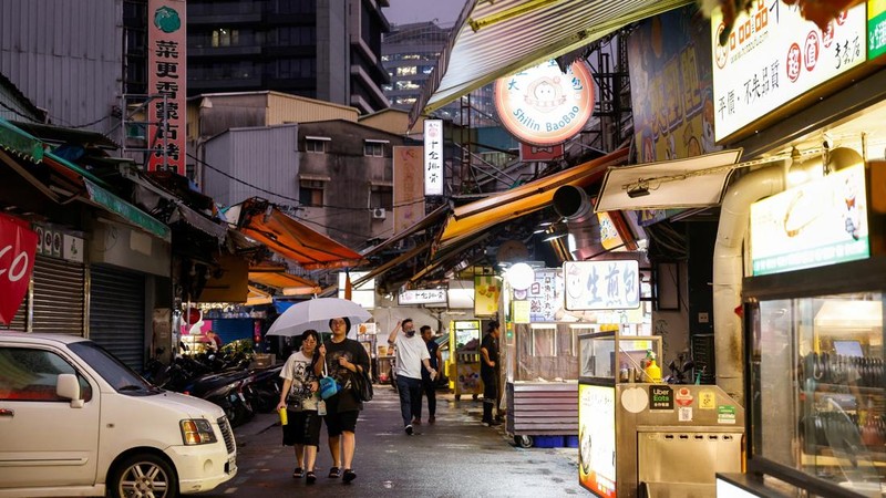 Orang-orang berjalan melewati pasar di tengah hujan saat Topan Champi mendekat, di Taipei, Taiwan, 22 Oktober 2026.