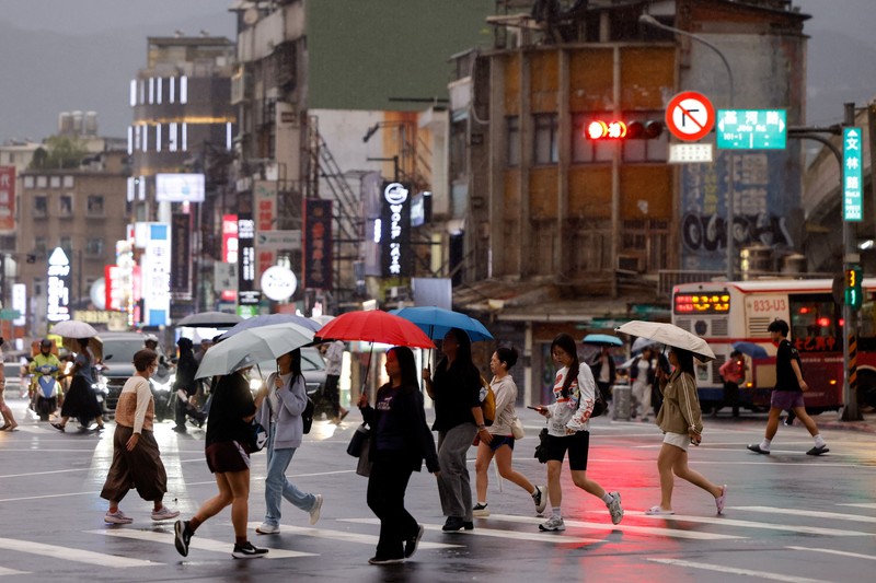 Orang-orang membawa payung di tengah hujan saat Topan Champi mendekat, di Taipei, Taiwan, 22 Oktober 2026. (REUTERS/Ann Wang)