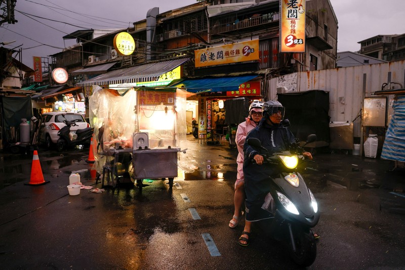 Orang-orang membawa payung di tengah hujan saat Topan Champi mendekat, di Taipei, Taiwan, 22 Oktober 2026. (REUTERS/Ann Wang)