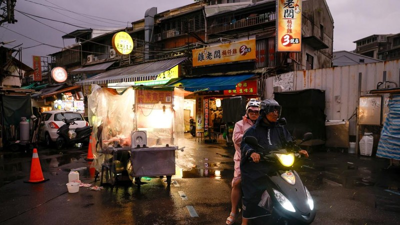 Orang-orang mengendarai skuter di sepanjang jalan yang basah saat Topan Champi mendekat, di Taipei, Taiwan, 22 Oktober 2026.