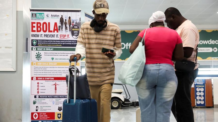 Para pelancong berada di dekat spanduk yang dipajang di pos pemeriksaan kesehatan di Bandara Internasional Murtala Muhammed, menyusul laporan mengenai satu kasus Ebola di Nigeria, di Lagos, Nigeria, 22 Oktober 2026.