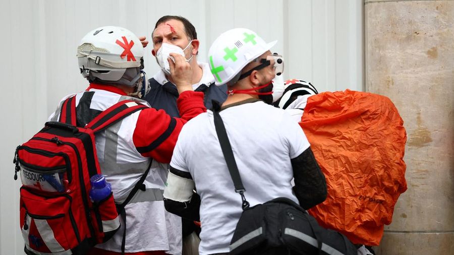 Street medics check an injured person during an authorised demonstration organised by labour unions in Paris as part of nationwide protests called by the "Yellow Vests" movement joined by French high school and university students against the cost of