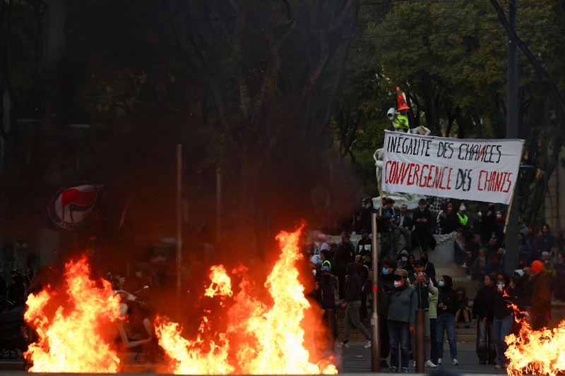 A fire burns next to a sign reading