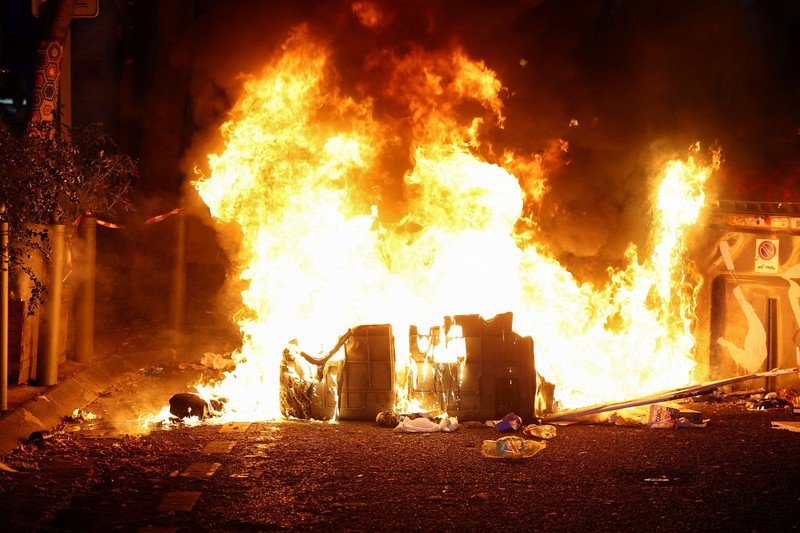 A fire burns next to a sign reading