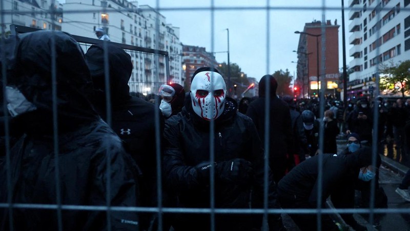 Masked protesters install a barricade amid clashes with French police during demonstration organised by labour unions in Paris as part of nationwide protests called by the "Yellow Vests" movement joined by French high school and university students a