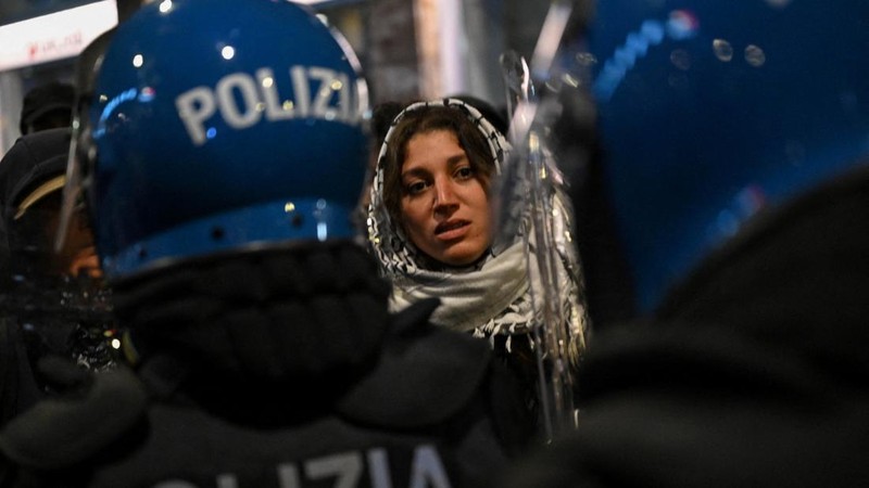 A woman faces riot police during clashes following a protest against the rising cost of living in Bologna, Italy, October 24, 2026. REUTERS/Michele Lapini     TPX IMAGES OF THE DAY