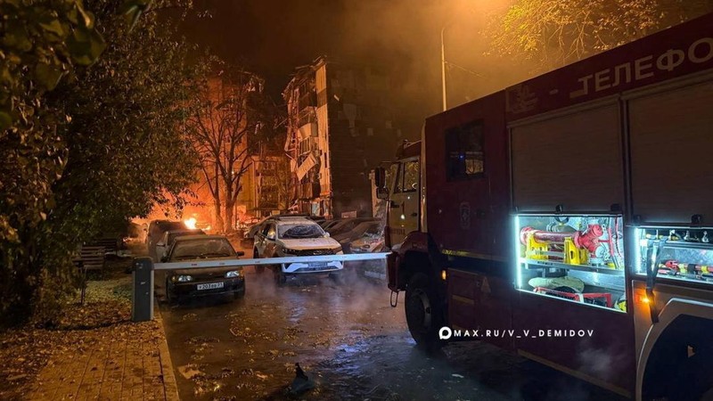 A view of a firefighting vehicle and damaged cars outside a residential multi-storey building hit by what local authorities described as a Ukrainian overnight drone strike, amid the Russia-Ukraine conflict, in the city of Belgorod, Russia, in this im