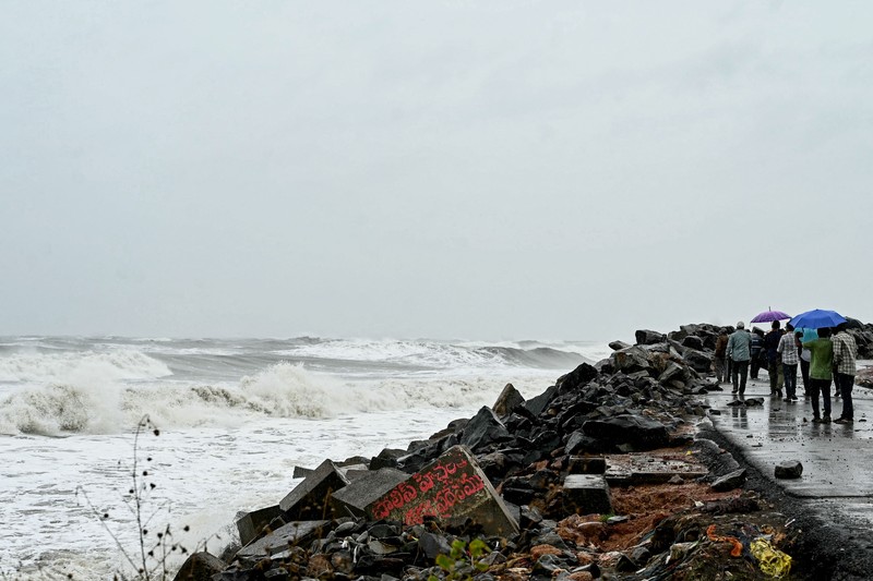 Seorang pria berjalan melewati perahu-perahu yang tertambat di sepanjang pelabuhan di tengah hujan dan angin kencang seiring mendekatnya Siklon Arnab, di Visakhapatnam, Andhra Pradesh, India, 27 Oktober 2026. (REUTERS/Ahamad Shaik)