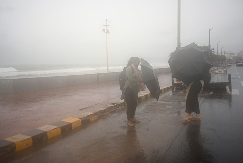 Seorang pria berjalan melewati perahu-perahu yang tertambat di sepanjang pelabuhan di tengah hujan dan angin kencang seiring mendekatnya Siklon Arnab, di Visakhapatnam, Andhra Pradesh, India, 27 Oktober 2026. (REUTERS/Ahamad Shaik)