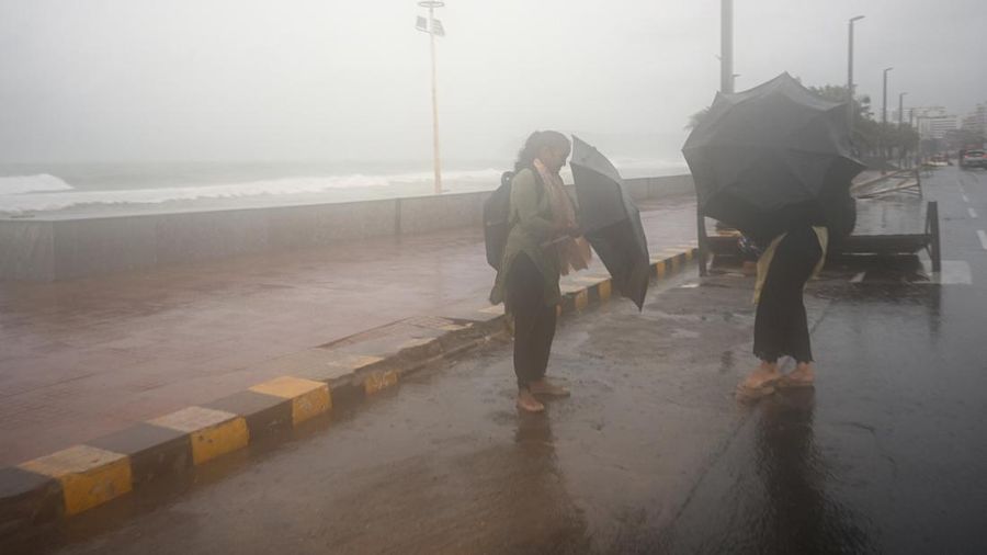Para wanita berlindung di bawah payung saat air pasang terjadi di tengah hujan dan angin kencang seiring mendekatnya Siklon Arnab, di Visakhapatnam, Andhra Pradesh, India, 27 Oktober 2026. (REUTERS/Ahamad Shaik)
