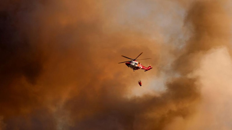 Sebuah helikopter pemadam kebakaran, yang terbang di tengah kepulan asap, menjatuhkan air untuk memadamkan kebakaran di Desa Guryong, Seoul, Korea Selatan, pada 27 Oktober 2026.