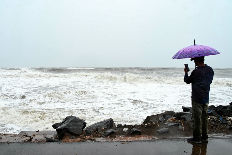 Seorang pria berjalan melewati perahu-perahu yang tertambat di sepanjang pelabuhan di tengah hujan dan angin kencang seiring mendekatnya Siklon Arnab, di Visakhapatnam, Andhra Pradesh, India, 27 Oktober 2026. (REUTERS/Ahamad Shaik)