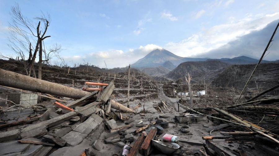 Foto yang diambil di Desa Kinahrejo ini memperlihatkan kehancuran pascaerupsi Gunung Merapi (di latar belakang), tepat di dekat rumah sosok yang dianggap sebagai "juru kunci" gunung tersebut, Mbah Marijan, di Sleman pada 28 Oktober 2010. (Photo by AD