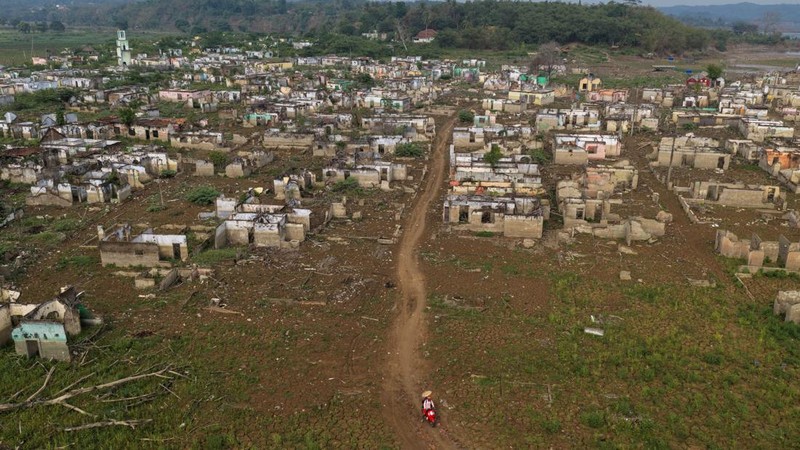 Tampilan dari drone memperlihatkan seorang pengendara melintas di dekat sisa-sisa Desa Somang yang muncul kembali setelah permukaan air di waduk Karian—sumber pasokan air untuk wilayah sekitarnya, termasuk Jakarta—menurun akibat kekeringan berkepanjangan yang dipicu oleh fenomena El Nino, di Lebak, Provinsi Banten, Indonesia, 23 Oktober 2026.