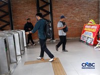 Sejumlah calon penumpang melintas di samping Karangan bunga di depan eskalator mati di Stasiun Bojonggede, Kab Bogor, Jawa Barat, Kamis, (29/10/2026). (CNBC Indonesia/Muhammad Sabki)