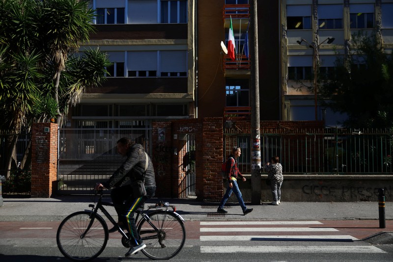 Seorang siswi mengangkat tangannya sementara Giovanni Pavese, guru musik, memperhatikan selama pelajaran di sebuah ruang kelas di sekolah komprehensif negeri 'Simona Giorgi', di Milan, Italia, 23 Oktober 2026. (REUTERS/Claudia Greco)