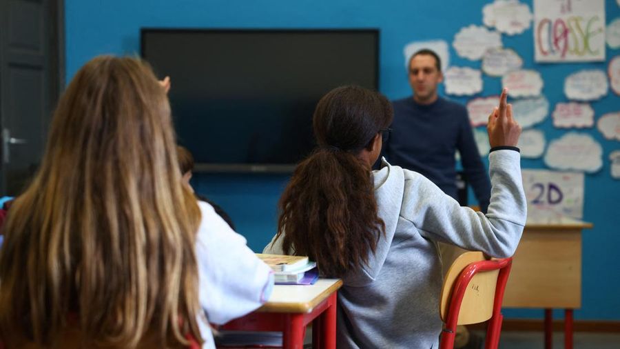 Seorang siswi mengangkat tangannya sementara Giovanni Pavese, guru musik, memperhatikan selama pelajaran di sebuah ruang kelas di sekolah komprehensif negeri 'Simona Giorgi', di Milan, Italia, 23 Oktober 2026. (REUTERS/Claudia Greco)