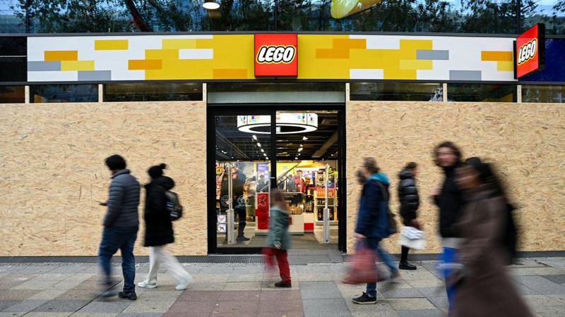 Orang-orang berjalan melewati sebuah toko Lego yang diamankan dengan papan kayu menjelang aksi protes yang diperkirakan akan dilakukan oleh gerakan pemuda